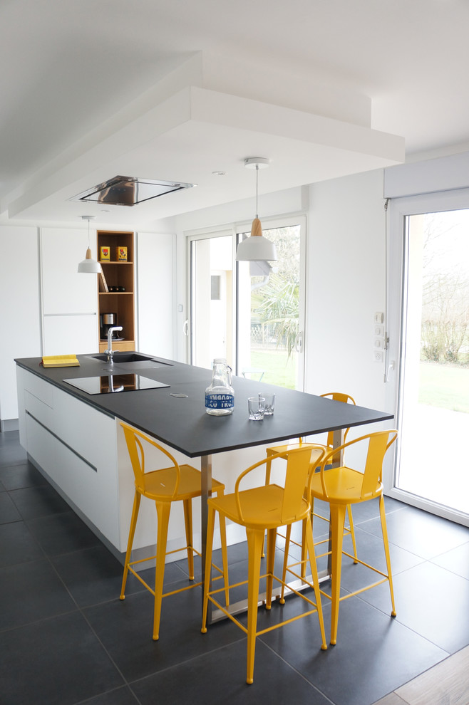 Photo of a mid-sized contemporary open plan kitchen in Nantes with an integrated sink, flat-panel cabinets, white cabinets, with island and concrete floors.