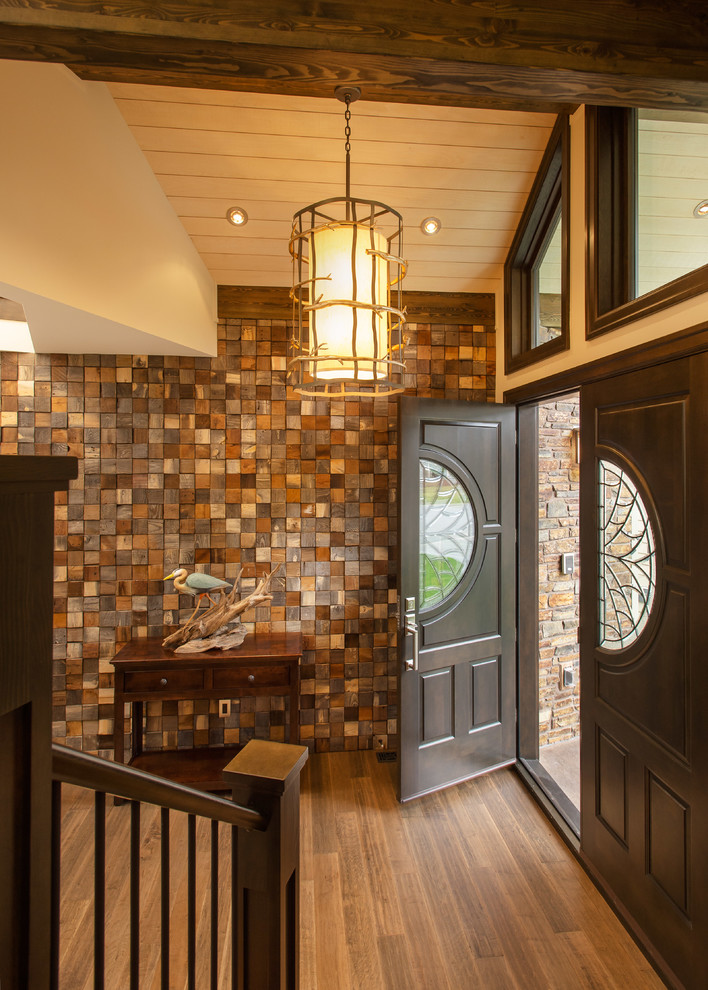 Large mountain style medium tone wood floor foyer photo in Vancouver with beige walls and a dark wood front door