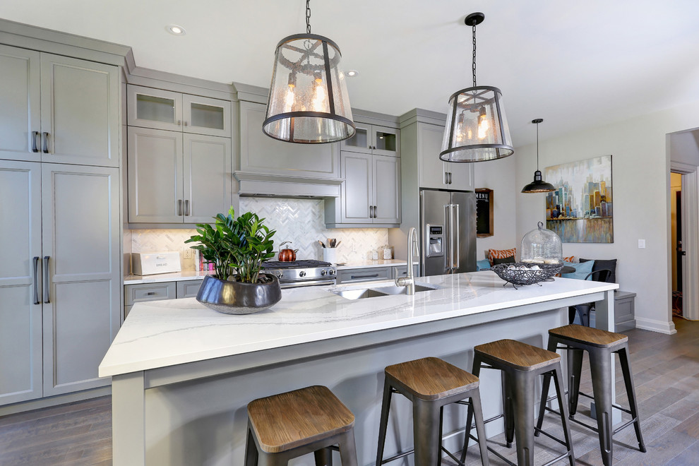 Transitional galley kitchen in Toronto with a double-bowl sink, recessed-panel cabinets, grey cabinets, marble benchtops, white splashback, stainless steel appliances, medium hardwood floors and with island.