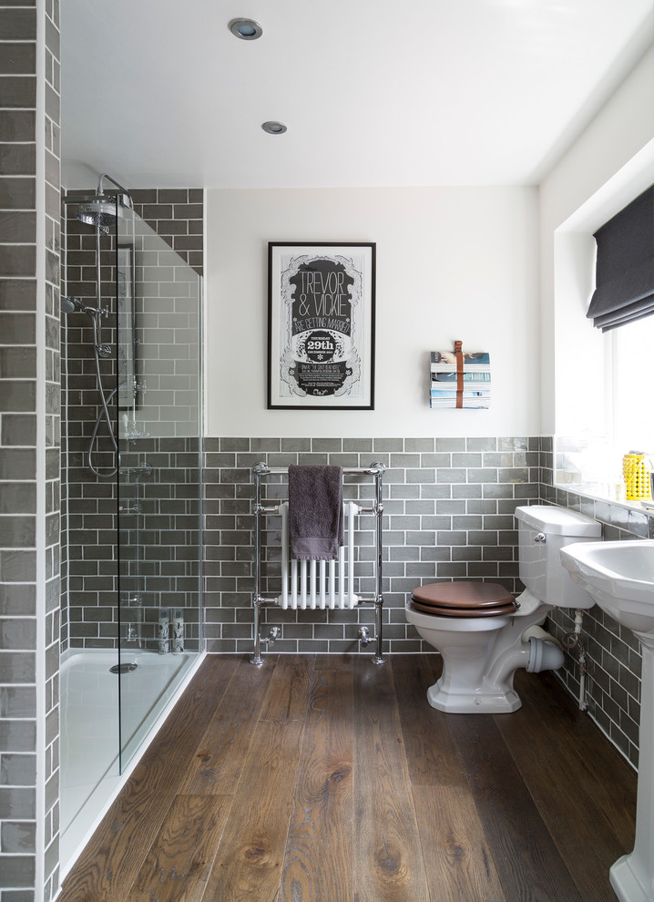 Inspiration for a traditional bathroom in Buckinghamshire with a pedestal sink, an alcove shower, a two-piece toilet, gray tile, subway tile, white walls, dark hardwood floors and brown floor.