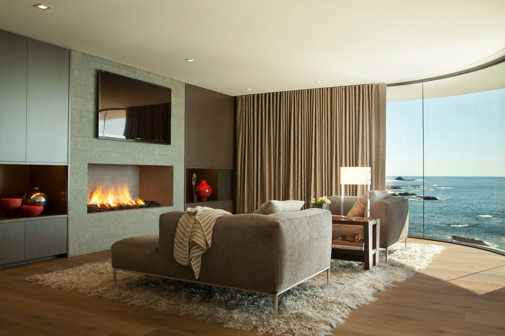 Expansive contemporary master bedroom in Orange County with grey walls, medium hardwood floors and a standard fireplace.