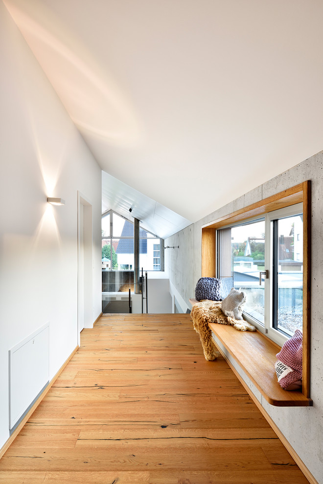This is an example of a contemporary hallway in Nuremberg with white walls, light hardwood floors and brown floor.