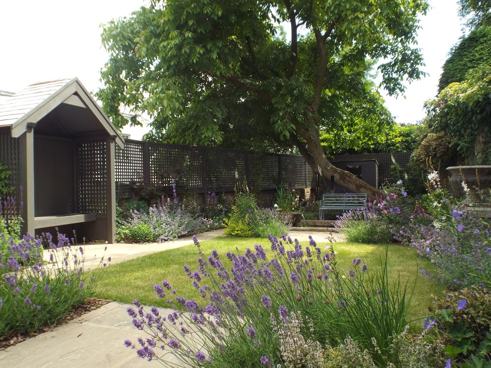 This is an example of a mid-sized traditional backyard partial sun garden in London with a garden path.