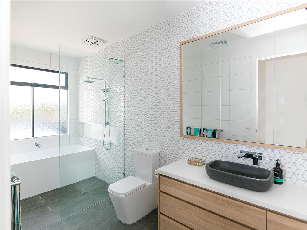 Large beach style master bathroom in Other with flat-panel cabinets, light wood cabinets, an alcove tub, a curbless shower, a one-piece toilet, white tile, white walls, a vessel sink, grey floor, an open shower, ceramic tile, porcelain floors, engineered quartz benchtops and white benchtops.