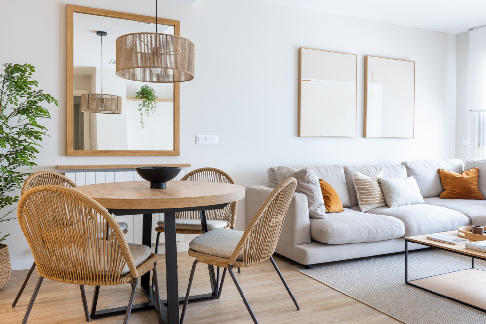 Ejemplo de comedor escandinavo grande con paredes beige, suelo de madera clara, suelo marrón y cuadros