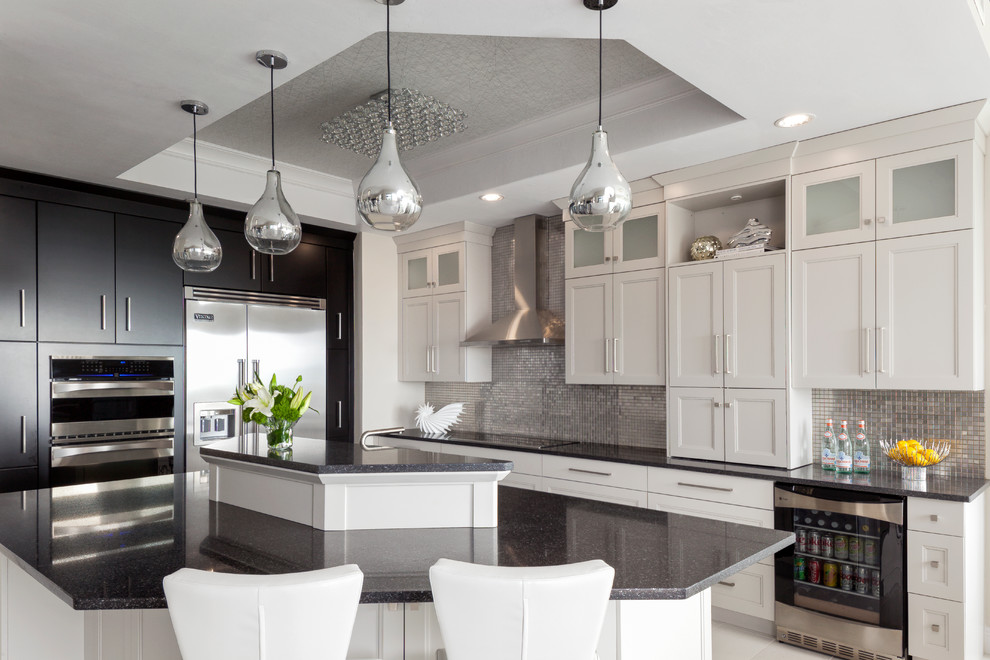 This is an example of a mid-sized beach style l-shaped open plan kitchen in Minneapolis with recessed-panel cabinets, white cabinets, quartz benchtops, metallic splashback, mosaic tile splashback, stainless steel appliances, porcelain floors, with island and white floor.
