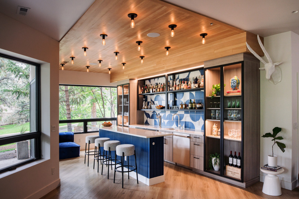 Idee per un angolo bar contemporaneo con lavello sottopiano, ante lisce, ante in legno chiaro, paraspruzzi blu, pavimento in legno massello medio, pavimento marrone e top bianco