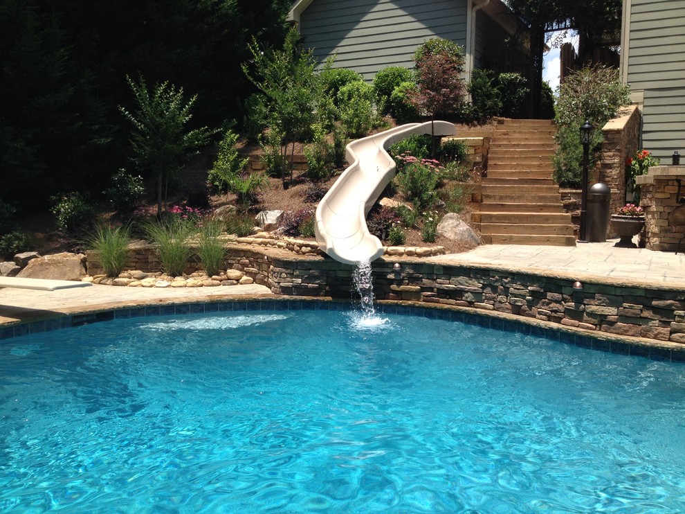 Inspiration for a mid-sized traditional backyard custom-shaped natural pool in Atlanta with a water slide and stamped concrete.