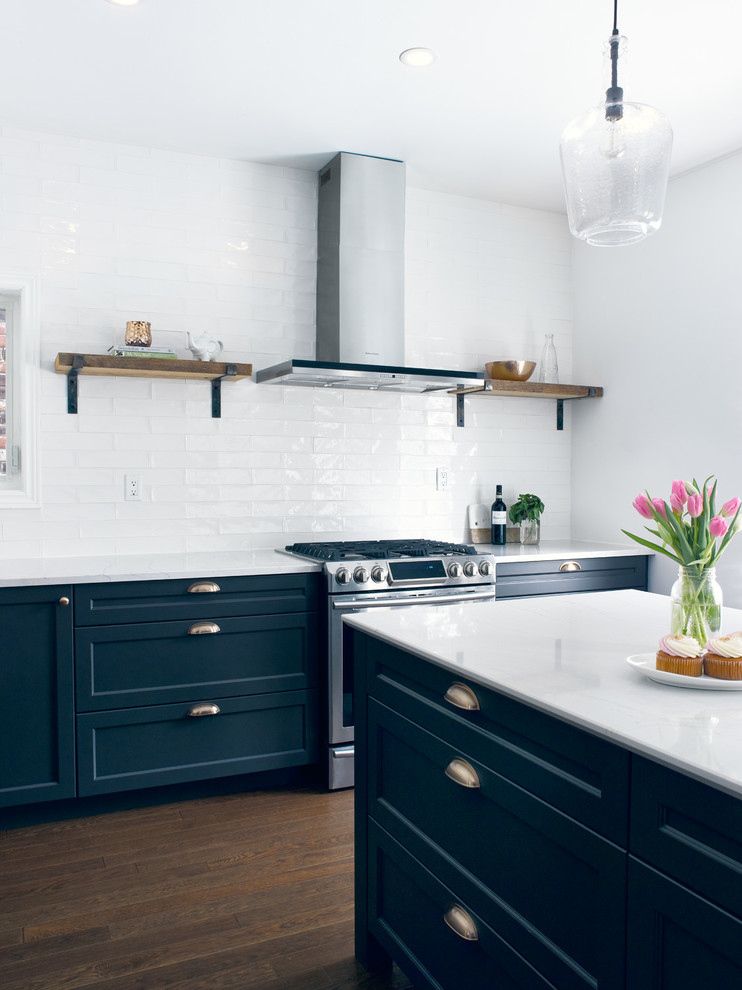 Mid-sized transitional l-shaped medium tone wood floor enclosed kitchen photo in Toronto with an undermount sink, recessed-panel cabinets, blue cabinets, quartz countertops, white backsplash, subway tile backsplash, stainless steel appliances and an island