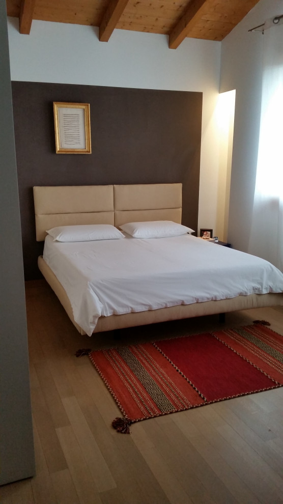Ejemplo de dormitorio principal actual pequeño con paredes grises y suelo de madera en tonos medios