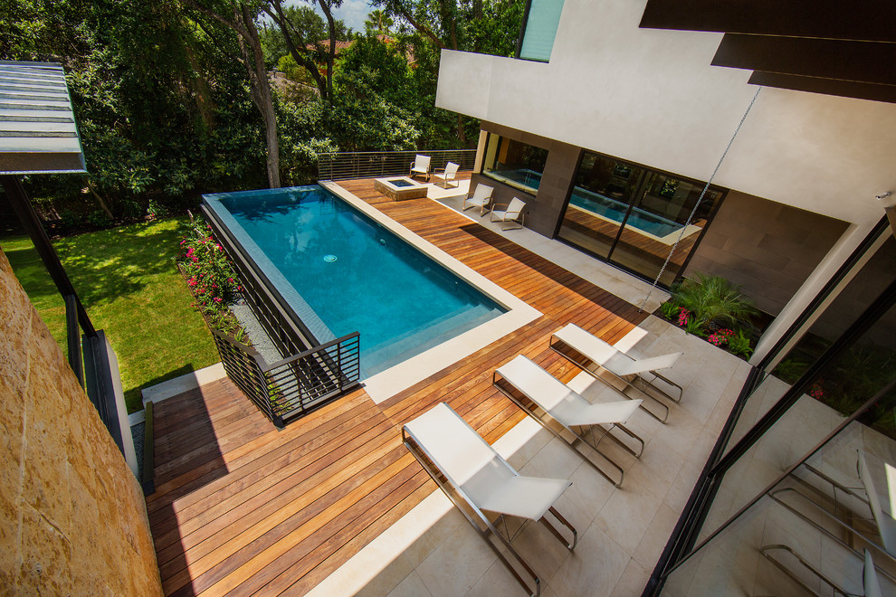 This is an example of a mid-sized modern backyard rectangular infinity pool in Austin with decking.