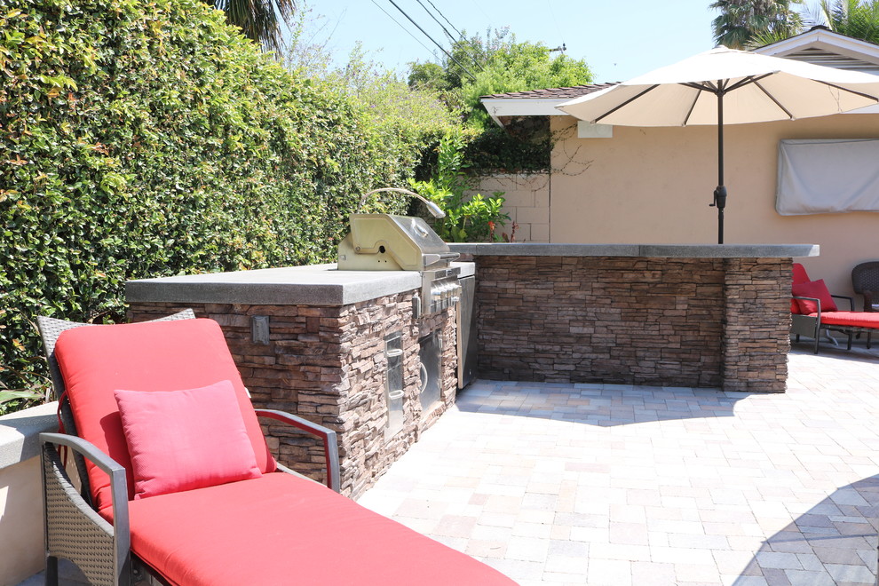 Photo of a tropical backyard garden in Orange County with concrete pavers.