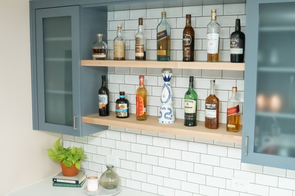 This is an example of a mid-sized contemporary single-wall home bar in Detroit with shaker cabinets, white splashback, ceramic splashback, porcelain floors, grey floor and white benchtop.