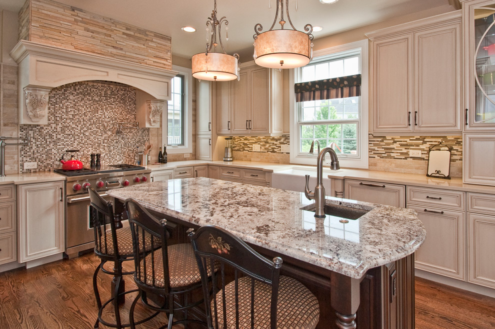 Transitional u-shaped enclosed kitchen photo in Chicago with a farmhouse sink, raised-panel cabinets, white cabinets, solid surface countertops, brown backsplash, glass tile backsplash and stainless steel appliances