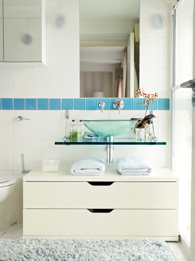 Contemporary bathroom in London with a vessel sink, flat-panel cabinets, white cabinets and white tile.