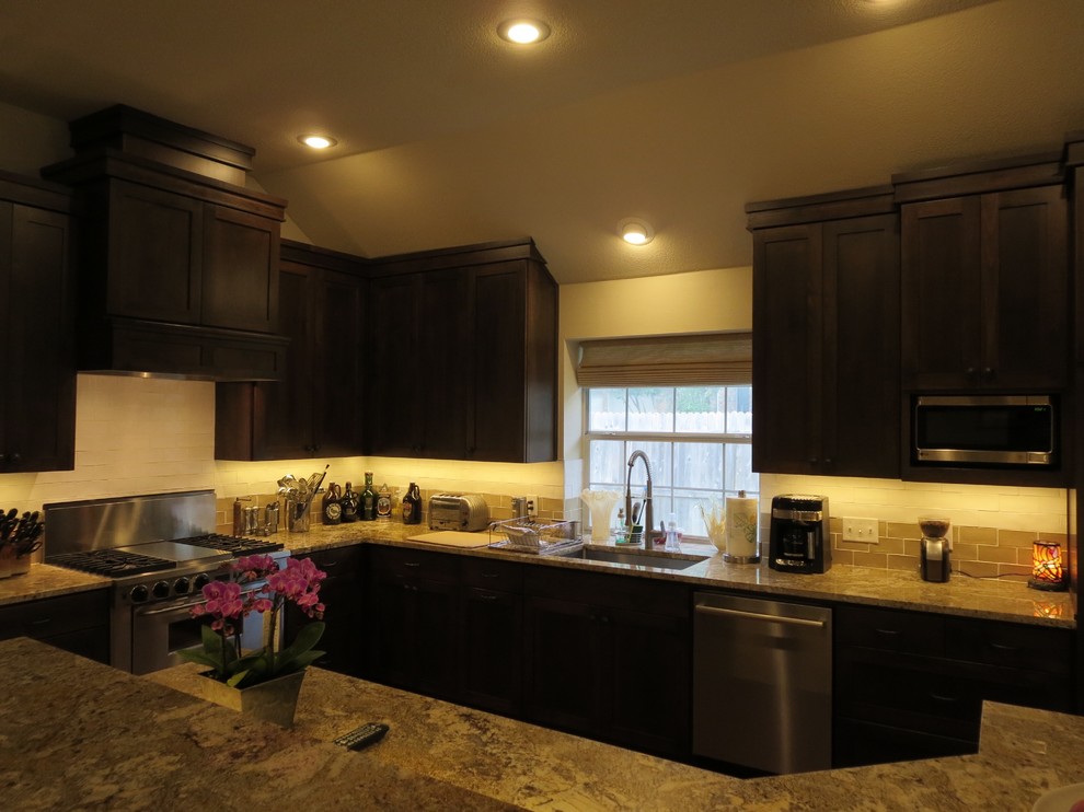 Example of a large transitional medium tone wood floor and brown floor eat-in kitchen design in Austin with an undermount sink, shaker cabinets, dark wood cabinets, granite countertops, multicolored backsplash, ceramic backsplash, stainless steel appliances and an island