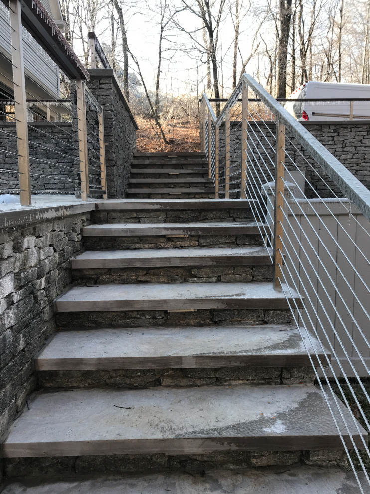This is an example of a large modern limestone straight staircase in New York with cable railing.