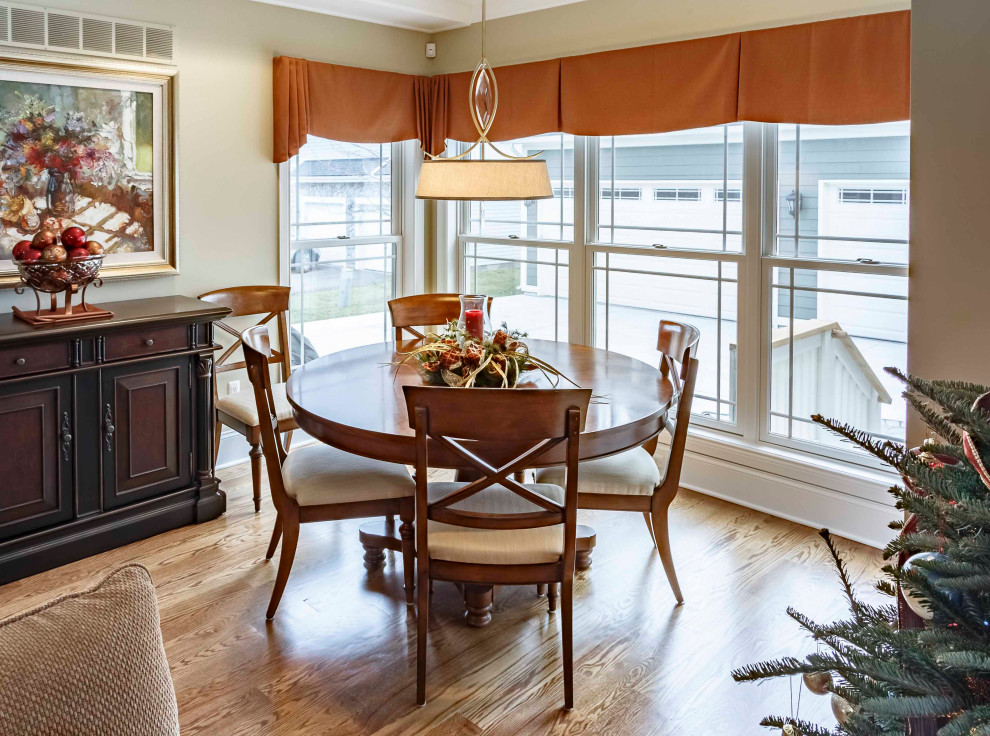 Photo of a mid-sized arts and crafts dining room in Detroit with brown walls, medium hardwood floors, brown floor, a standard fireplace, a wood fireplace surround, recessed and wallpaper.