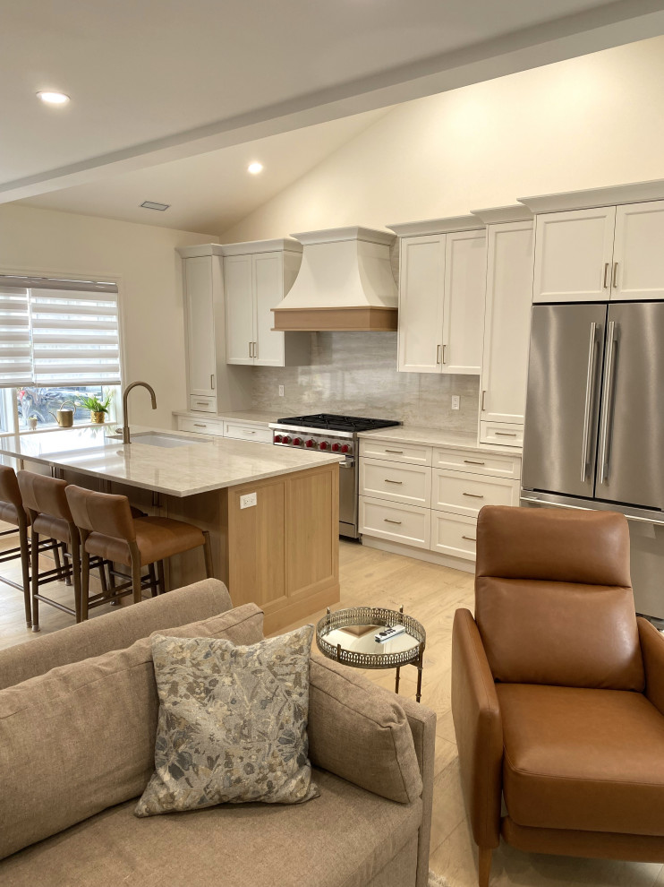 Open concept kitchen - small transitional galley light wood floor and vaulted ceiling open concept kitchen idea in Toronto with an undermount sink, recessed-panel cabinets, white cabinets, quartz countertops, quartz backsplash and stainless steel appliances