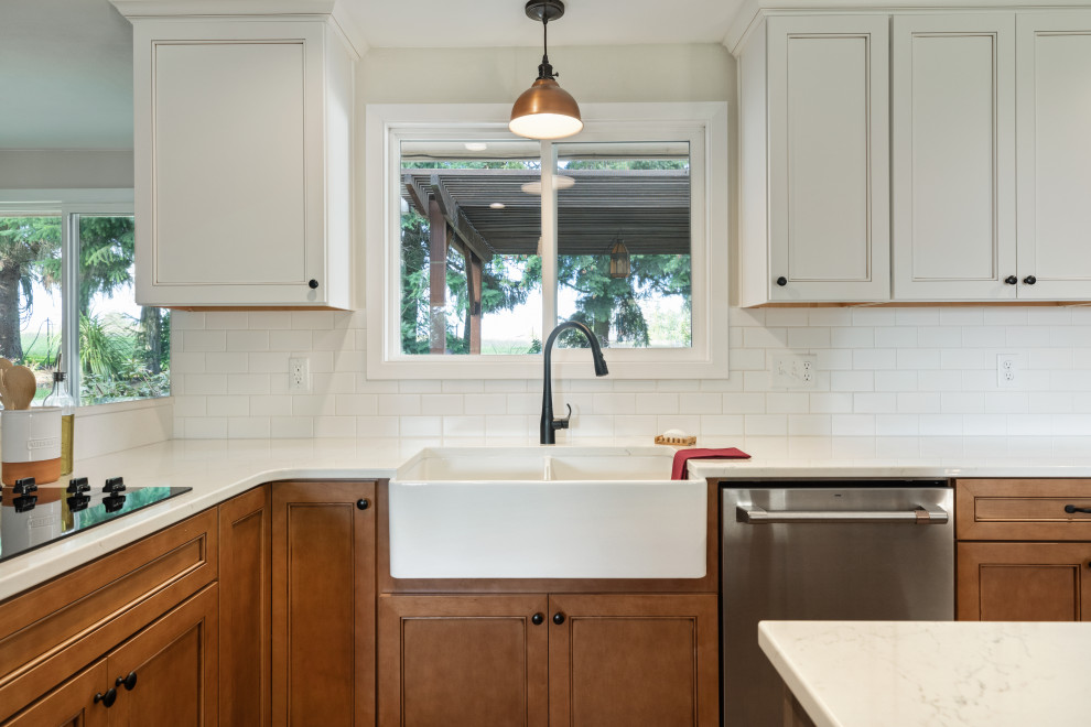 Inspiration for a mid-sized transitional l-shaped medium tone wood floor and brown floor eat-in kitchen remodel with a farmhouse sink, shaker cabinets, white cabinets, quartz countertops, white backsplash, subway tile backsplash, stainless steel appliances, an island and white countertops