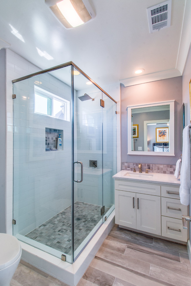 Design ideas for a mid-sized transitional 3/4 bathroom in Los Angeles with shaker cabinets, white cabinets, a corner shower, white tile, subway tile, purple walls, medium hardwood floors, an undermount sink, brown floor and a hinged shower door.