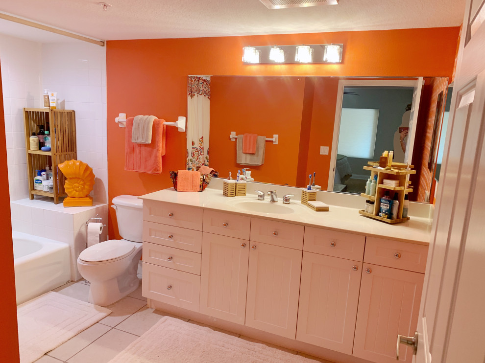 Large beach style family bathroom in Orlando with beaded cabinets, white cabinets, a built-in bath, a two-piece toilet, orange tiles, orange walls, ceramic flooring, laminate worktops, multi-coloured floors, multi-coloured worktops, a single sink, a built in vanity unit and wallpapered walls.