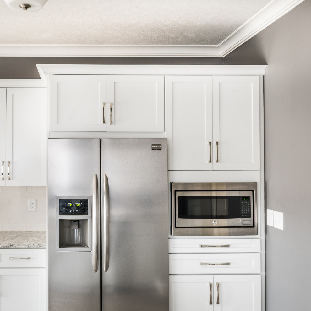Inspiration for a mid-sized transitional galley vinyl floor and beige floor open concept kitchen remodel with an undermount sink, recessed-panel cabinets, white cabinets, quartz countertops, white backsplash, stone tile backsplash, stainless steel appliances, a peninsula and multicolored countertops
