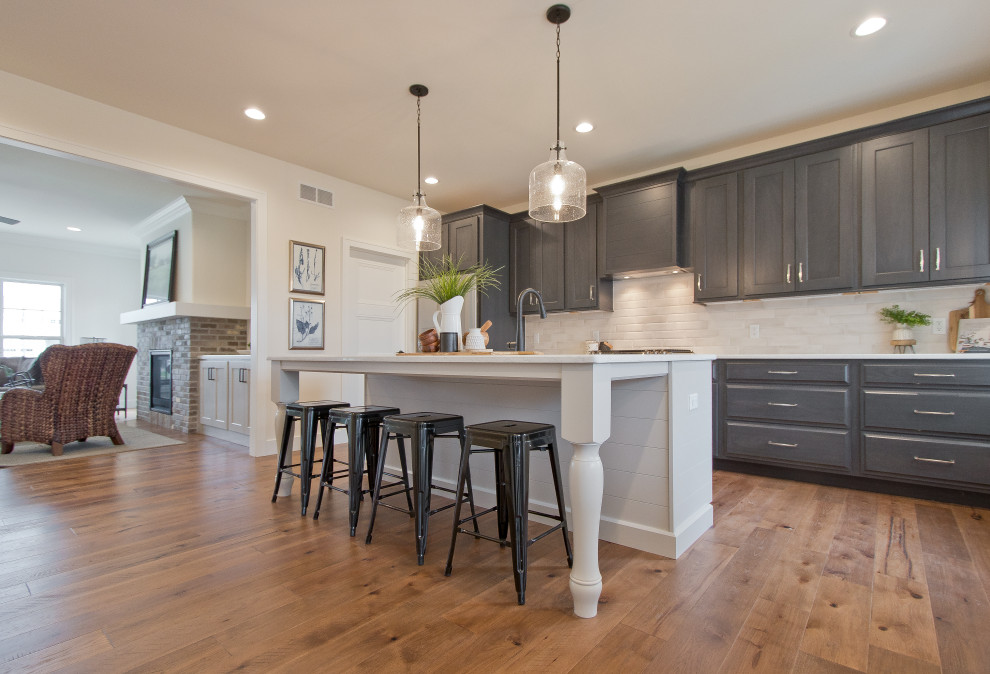 Eat-in kitchen - transitional single-wall light wood floor and brown floor eat-in kitchen idea with an undermount sink, raised-panel cabinets, dark wood cabinets, quartz countertops, white backsplash, brick backsplash, stainless steel appliances, an island and white countertops