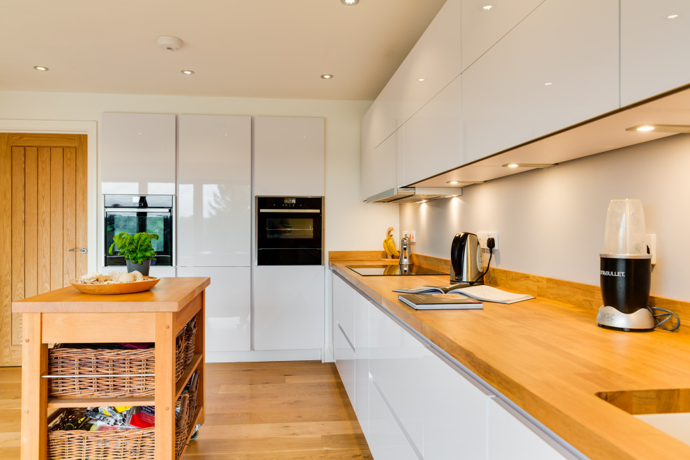 Ispirazione per una cucina minimalista di medie dimensioni con ante lisce, ante bianche, top in legno e pavimento in legno massello medio