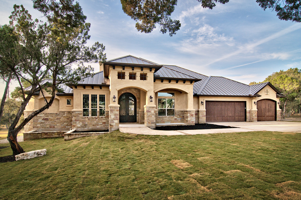 This is an example of a mediterranean exterior in Austin with stone veneer and a metal roof.