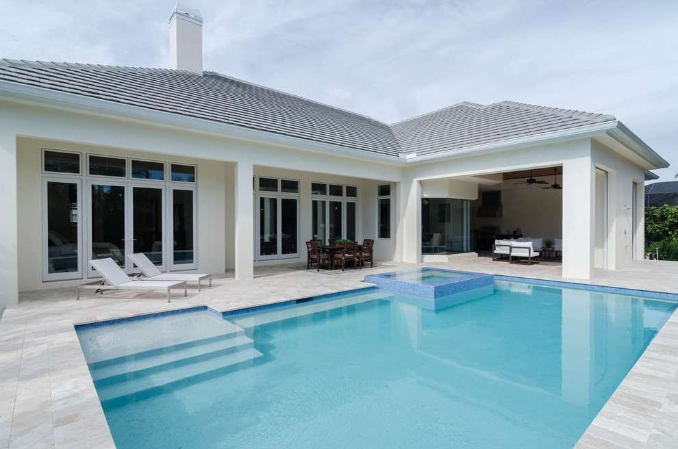This is an example of a large contemporary backyard rectangular lap pool in Miami with a hot tub and natural stone pavers.