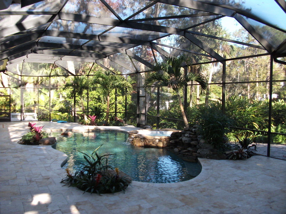 This is an example of a mid-sized traditional backyard custom-shaped lap pool in Tampa with a pool house and stamped concrete.