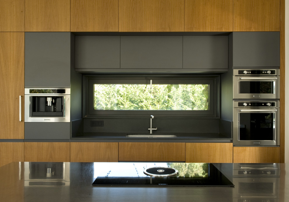 This is an example of a large contemporary galley open plan kitchen in Other with flat-panel cabinets, light wood cabinets, marble worktops, an island and black worktops.