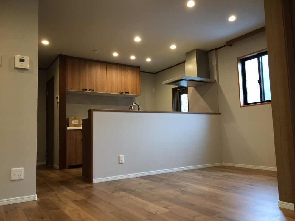 Mid-sized country single-wall open plan kitchen in Nagoya with brown cabinets, solid surface benchtops, brown splashback, plywood floors, brown floor, brown benchtop and wallpaper.