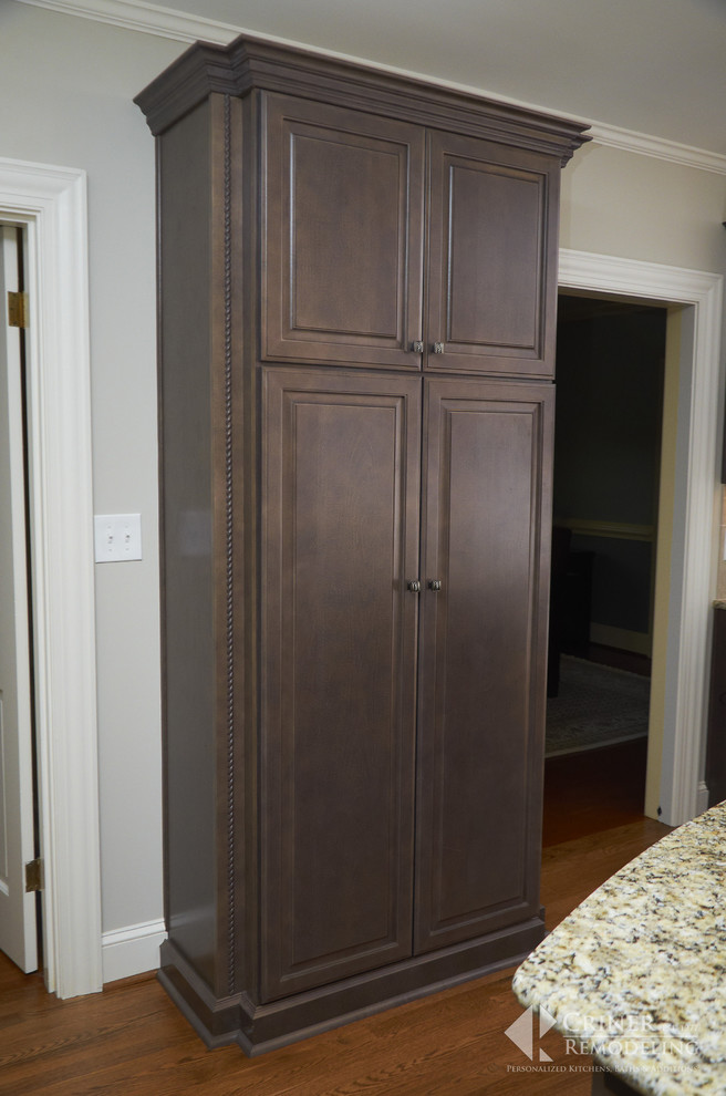 Example of a transitional light wood floor eat-in kitchen design with shaker cabinets, dark wood cabinets, granite countertops, beige backsplash, glass tile backsplash, stainless steel appliances and an island