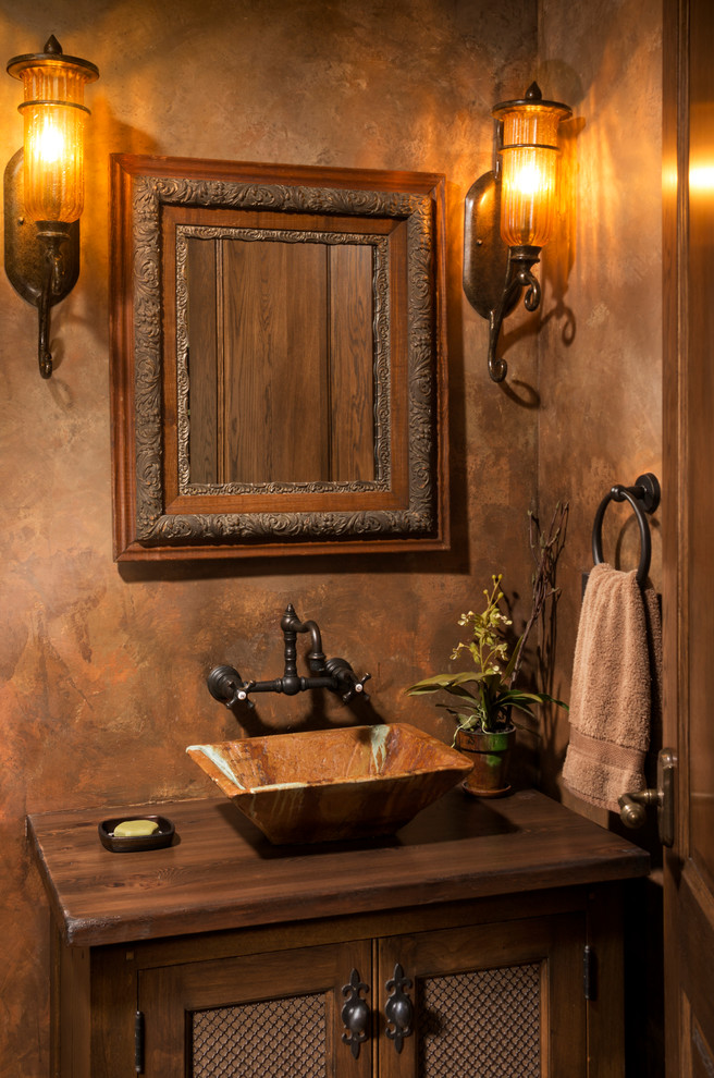 Small traditional powder room in Minneapolis with a vessel sink, wood benchtops, furniture-like cabinets, dark wood cabinets, brown walls and brown benchtops.