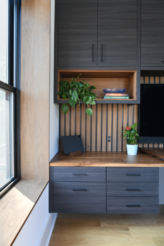 Ejemplo de despacho contemporáneo grande sin chimenea con paredes blancas, suelo de madera clara, escritorio empotrado, suelo marrón y madera