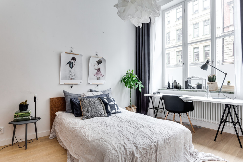Mid-sized scandinavian master bedroom in Stockholm with white walls, light hardwood floors and no fireplace.