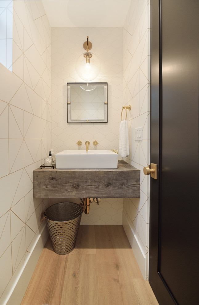 Photo of a contemporary powder room in Orange County with white tile, white walls, light hardwood floors, a vessel sink, wood benchtops, beige floor and grey benchtops.