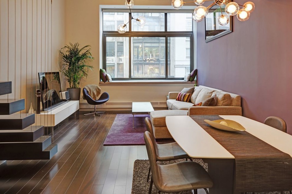 This is an example of a mid-sized contemporary open concept living room in New York with purple walls, dark hardwood floors, no fireplace, a freestanding tv and brown floor.