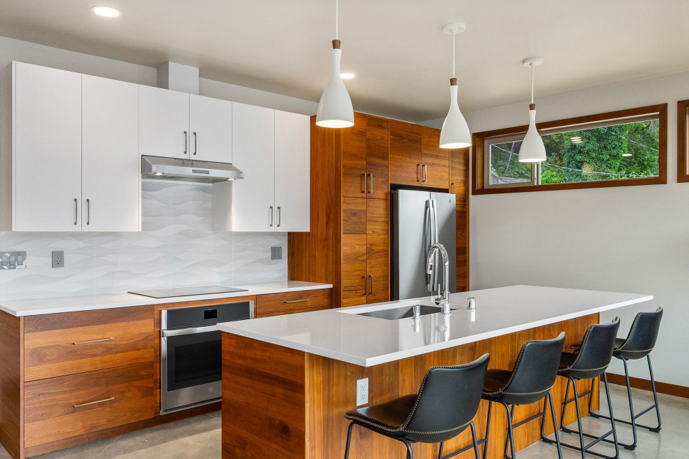 Example of a mid-sized transitional eat-in kitchen design in Seattle with flat-panel cabinets, quartz countertops, stainless steel appliances and an island