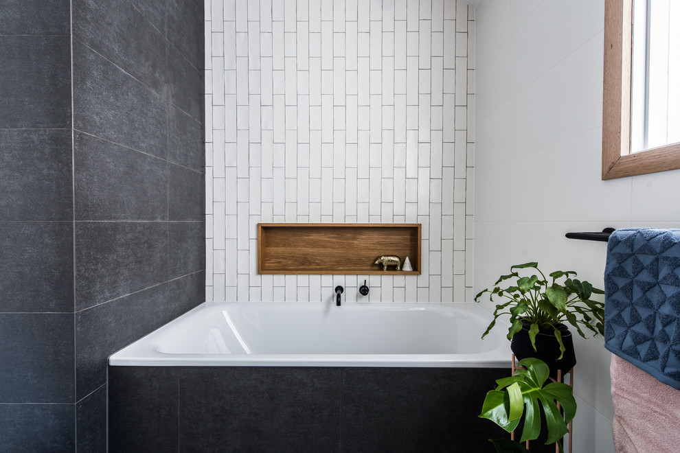 This is an example of a mid-sized contemporary 3/4 bathroom in Melbourne with flat-panel cabinets, medium wood cabinets, a drop-in tub, a corner shower, white tile, ceramic tile, white walls, porcelain floors, a vessel sink, engineered quartz benchtops, black floor and a hinged shower door.