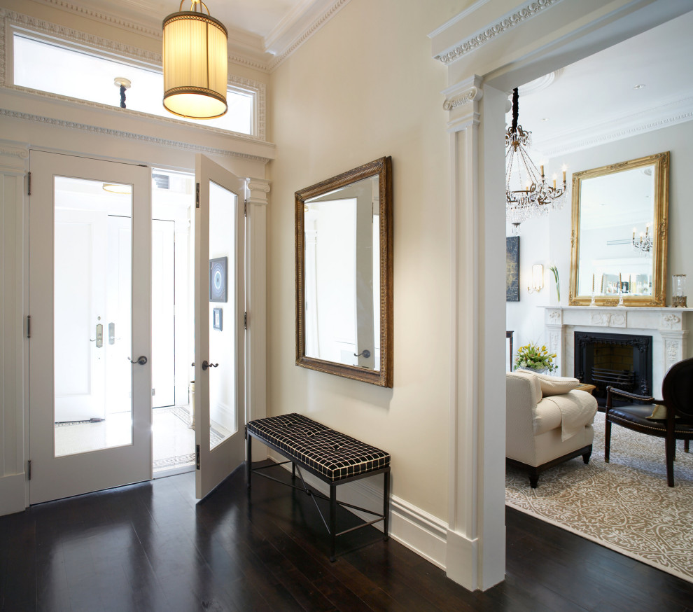 This is an example of a large transitional vestibule in New York with beige walls, dark hardwood floors, a single front door, a medium wood front door and exposed beam.