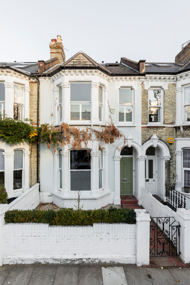 White traditional two floor detached house in London with a pitched roof, a shingle roof and a grey roof.