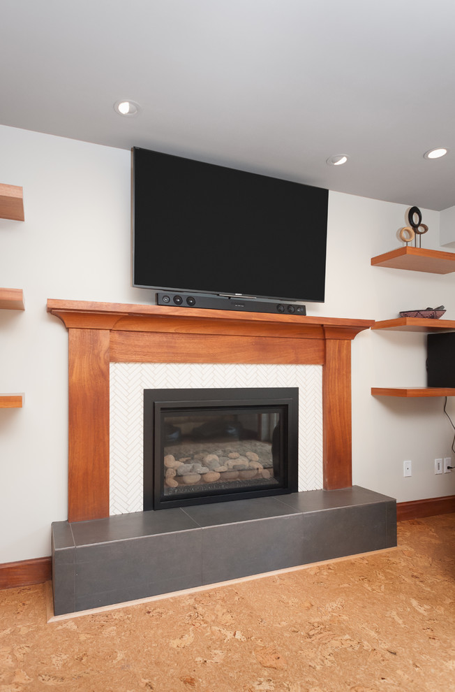 Design ideas for a mid-sized midcentury basement in Portland with white walls, cork floors, a standard fireplace, a tile fireplace surround and brown floor.