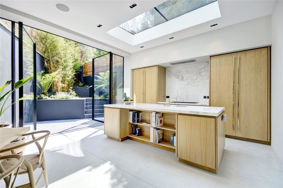 Design ideas for a contemporary galley open plan kitchen in London with an undermount sink, flat-panel cabinets, light wood cabinets, marble benchtops, white splashback, stone slab splashback, concrete floors, with island and grey floor.