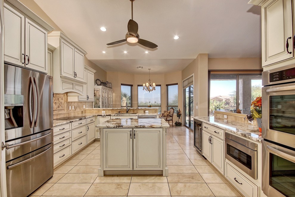 This is an example of a mid-sized traditional u-shaped eat-in kitchen in Phoenix with an undermount sink, raised-panel cabinets, white cabinets, granite benchtops, beige splashback, glass tile splashback, stainless steel appliances, with island, beige floor and white benchtop.