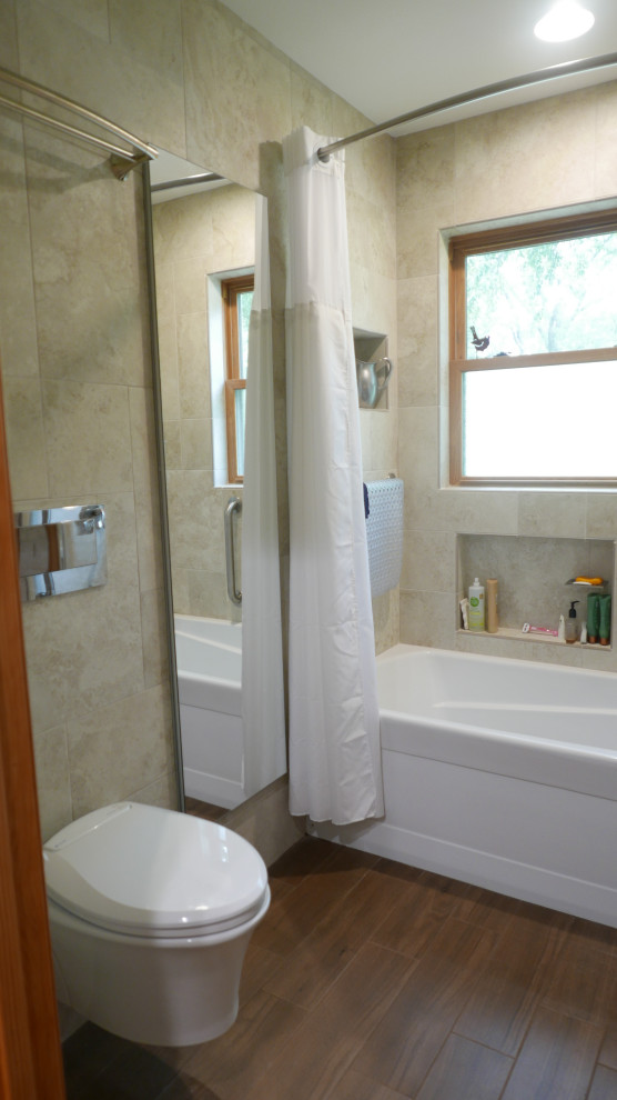 Photo of a mid-sized contemporary kids bathroom in Other with an alcove tub, a shower/bathtub combo, a wall-mount toilet, beige tile, porcelain tile, porcelain floors, a wall-mount sink, brown floor, a shower curtain, a niche and a single vanity.