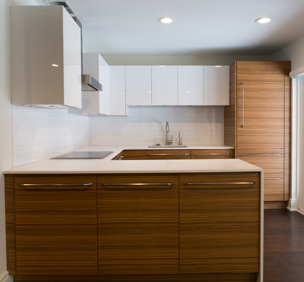 This is an example of a mid-sized contemporary l-shaped eat-in kitchen in New York with an undermount sink, flat-panel cabinets, medium wood cabinets, quartzite benchtops, white splashback, dark hardwood floors, with island, glass tile splashback and panelled appliances.