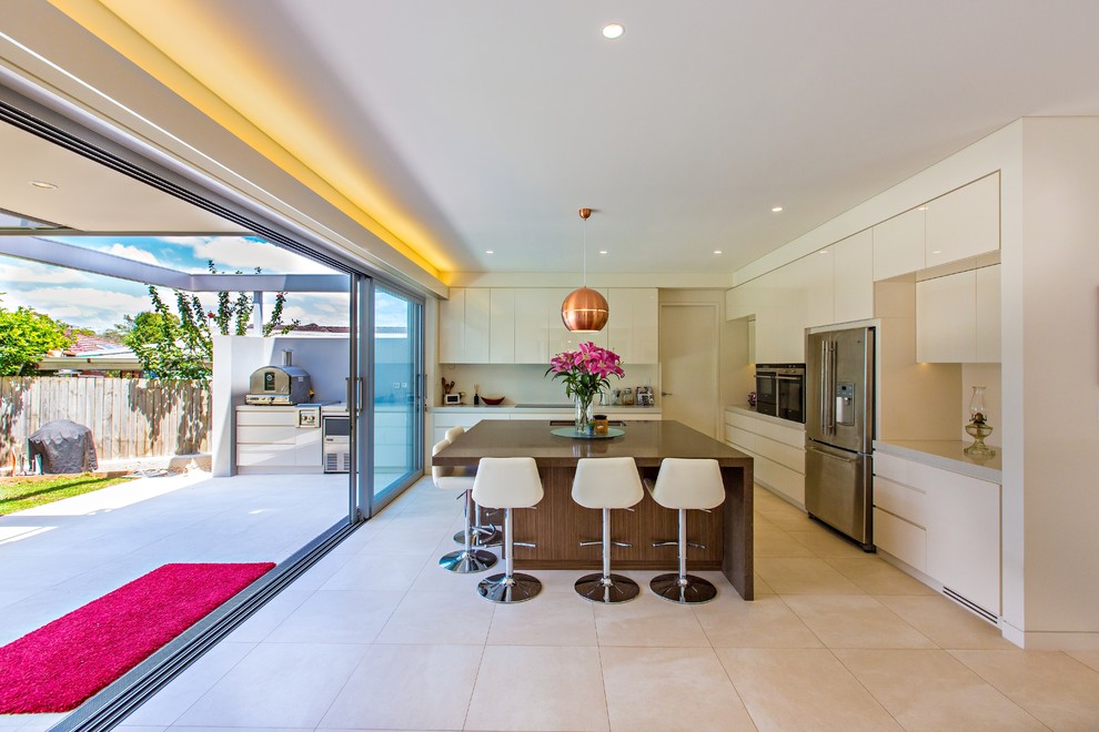 Photo of a contemporary l-shaped kitchen in Sydney with an undermount sink, flat-panel cabinets, white cabinets, stainless steel appliances and with island.